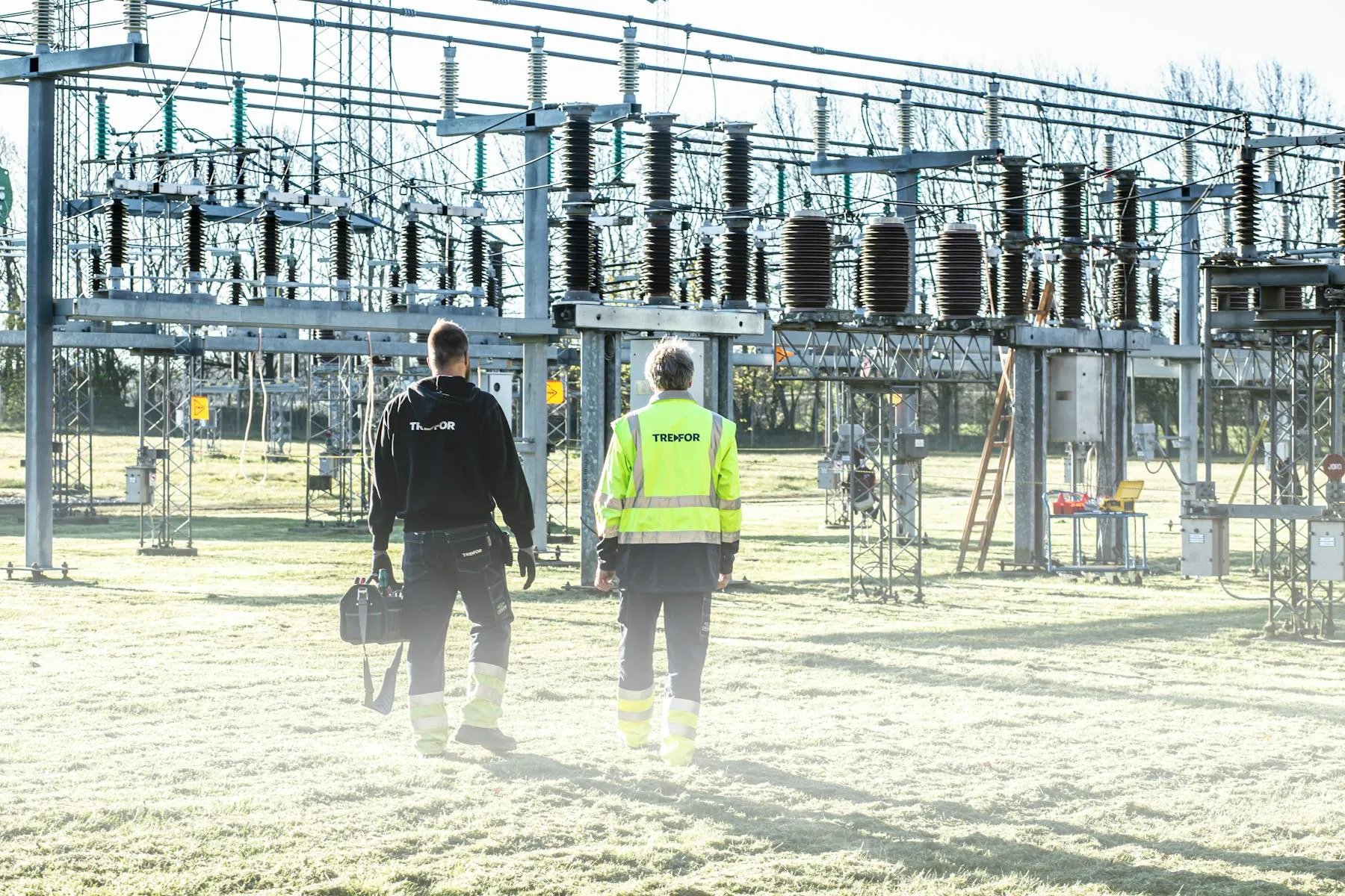 Utility engineers walking through a high-voltage electrical transformer substation — Entogo distribution-transformer customer site