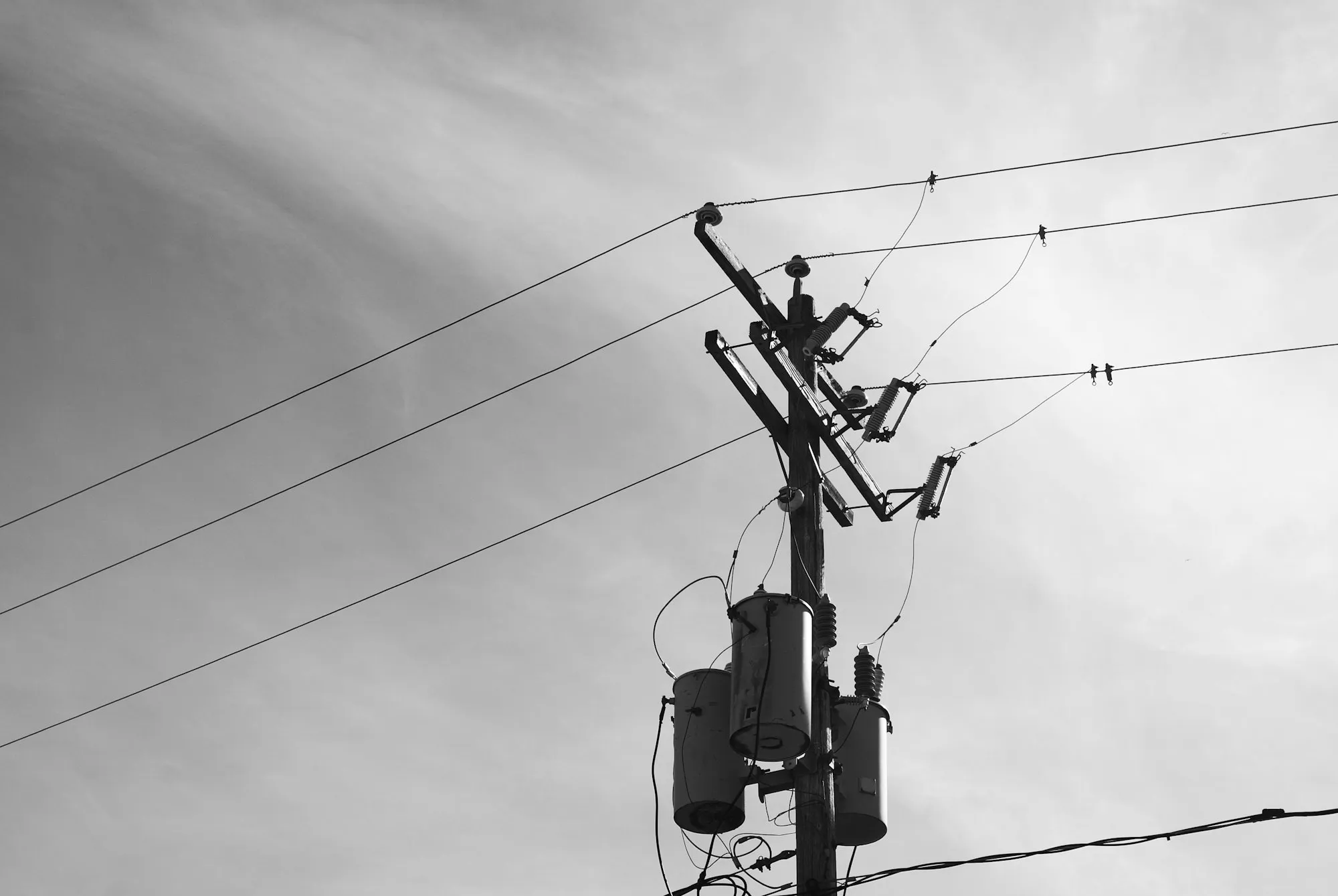 Banco de transformadores de distribución tipo poste sobre un poste de media tensión contra el cielo, el tipo de equipo regulado en México