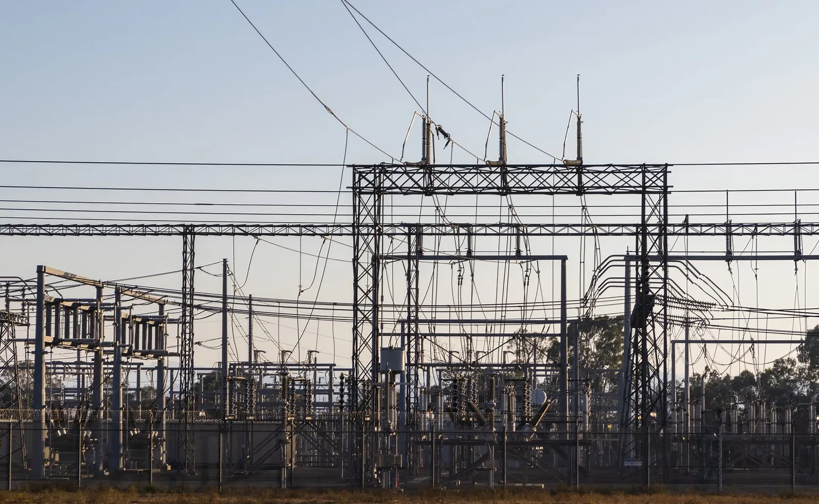 High-voltage electrical substation at dusk with transformers, busbars and overhead conductors silhouetted against the sky — the transformation and distribution backbone Entogo supplies as coordinated, factory-tested packages