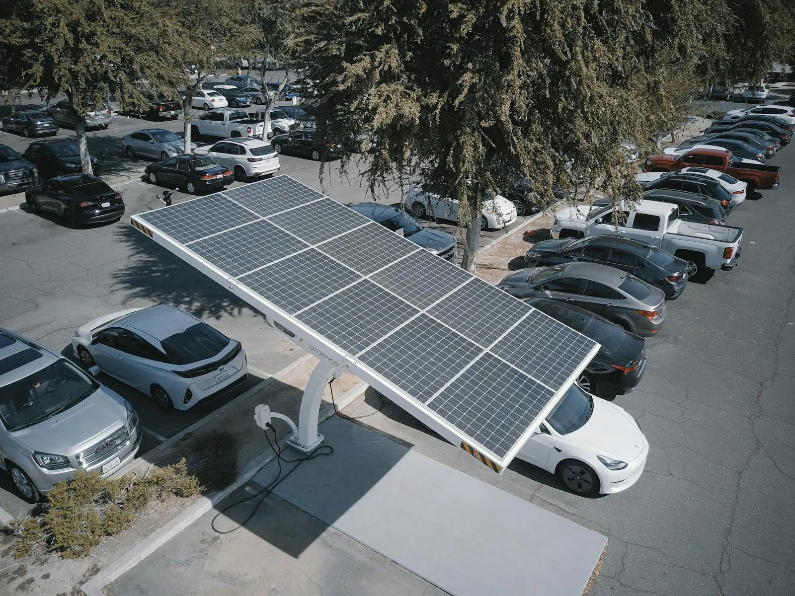 Aerial view of a parking-lot solar canopy with integrated EV charging serving electric vehicles below — the on-site PV-storage-charging environment Entogo delivers as one engineered solar-storage-charging package
